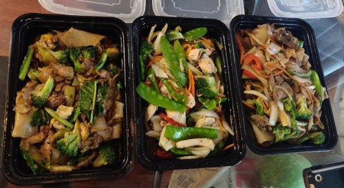 Three black containers filled with colorful stir-fried dishes featuring vegetables, chicken, and noodles.