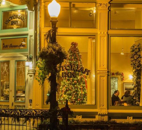 A warmly lit Victorian inn with a decorated Christmas tree visible through the window, creating a cozy holiday atmosphere.