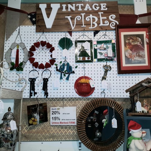 A display of vintage items including keys, decor, and a mirror, with a sign reading "Vintage Vibes" and price tags.
