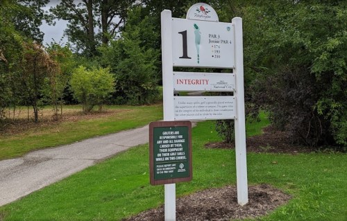 Sign for the first hole of a golf course, featuring the number 1, par details, and a message about integrity and safety.