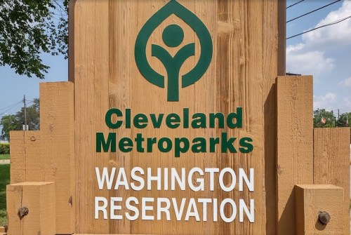 Sign for Cleveland Metroparks Washington Reservation, featuring a green logo and wooden background.
