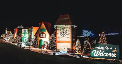 A festive scene featuring colorful houses, a large clock tower, and Christmas trees, illuminated at night with holiday lights.