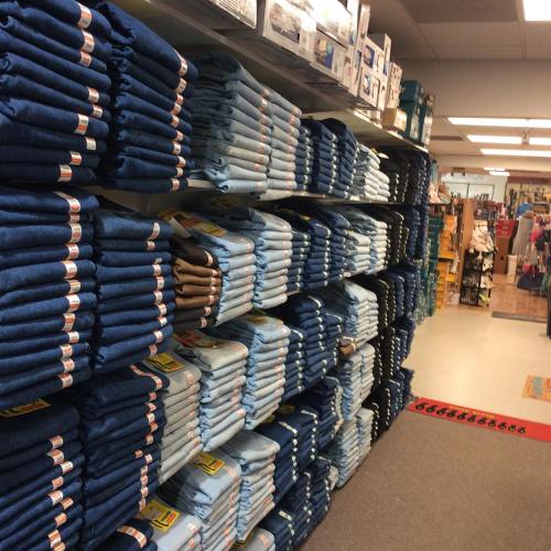 A store shelf displaying neatly stacked blue and beige towels, with various products visible in the background.