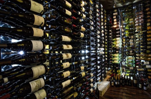 A well-organized wine cellar with rows of bottles illuminated by soft lights, showcasing a variety of wines.