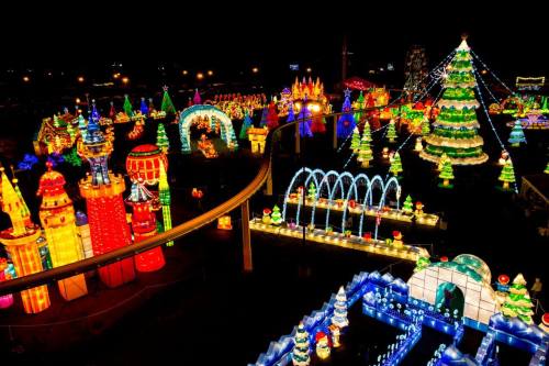 A vibrant display of colorful lights and decorations, featuring trees, castles, and festive structures at night.