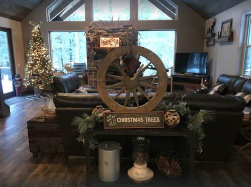 Cozy living room decorated for Christmas, featuring a tree, rustic decor, and a wagon wheel centerpiece.