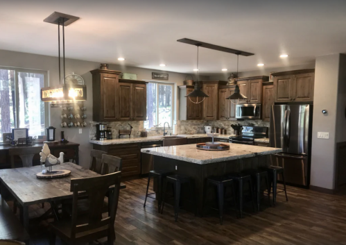 Modern kitchen with wooden cabinets, granite countertops, and a dining area featuring a large table and chairs.