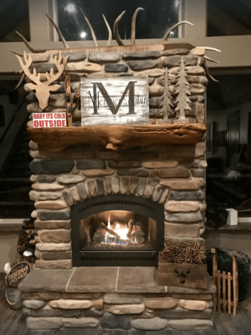 Cozy stone fireplace with a wooden mantel, antler decor, and a warm fire, creating a rustic, inviting atmosphere.