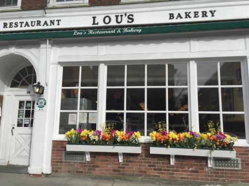 Exterior of Lou's Bakery with large windows and colorful flower boxes filled with tulips.