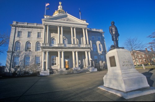 A historic building with a golden dome and columns, featuring a statue of Daniel Webster in the foreground.