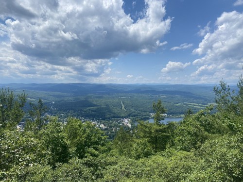A panoramic view of lush green hills and valleys under a partly cloudy sky.