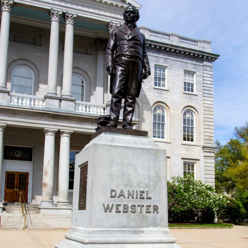 Statue of Daniel Webster in front of a historic building with columns and steps.