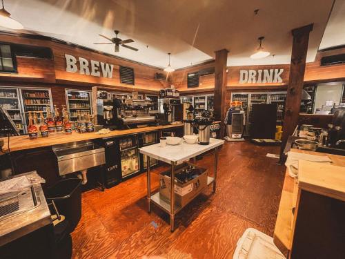 A cozy café interior with wooden accents, featuring a coffee bar, brewing equipment, and shelves of beverages.