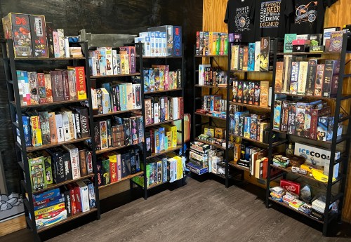 A cozy room filled with shelves of various board games, neatly organized and colorful.