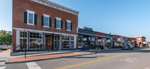 Historic brick buildings line a street, featuring shops and a clear blue sky above.
