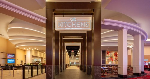 Entrance to "The Kitchens," a modern buffet experience, featuring stylish decor and bright signage.