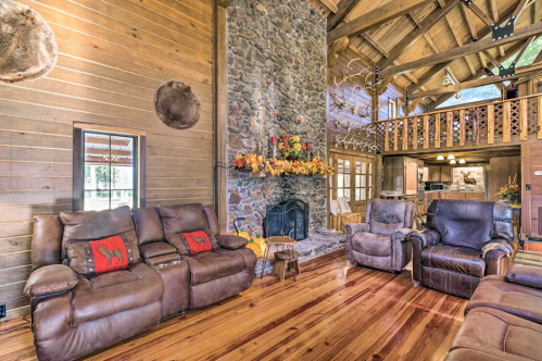 Cozy living room with stone fireplace, wooden walls, and leather recliners, decorated with autumn accents.