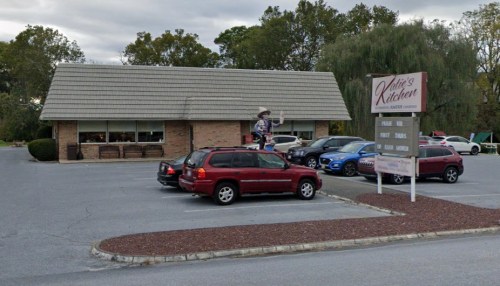 A restaurant named "Kelley's Kitchen" with a parking lot filled with cars and a large figure outside.