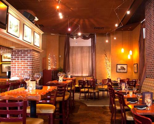 Cozy restaurant interior with wooden tables, red chairs, and warm lighting, featuring elegant decor and a welcoming atmosphere.