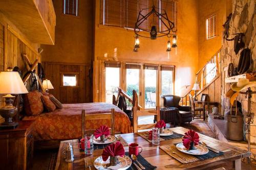 Cozy rustic room with a bed, dining table set for four, and large windows overlooking a patio. Warm, inviting decor.