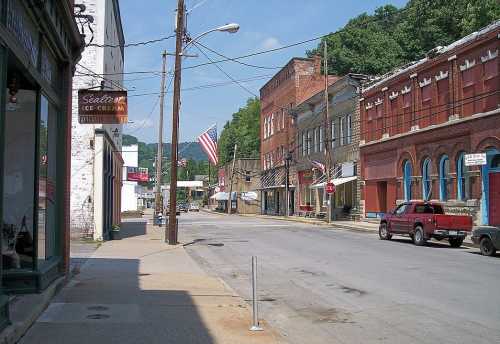 A quiet street scene featuring historic buildings, an American flag, and a red truck parked along the road.