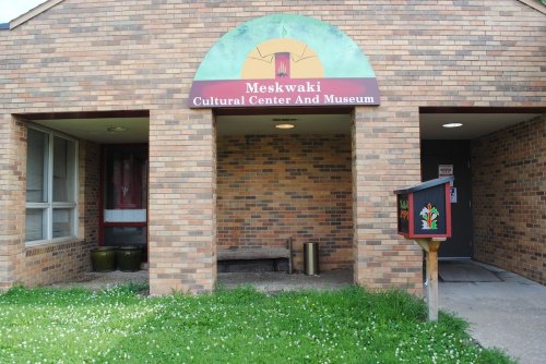 Exterior of the Meskwaki Cultural Center and Museum, featuring a sign and a small mailbox in front of a brick building.