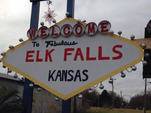 Welcome sign for Elk Falls, Kansas, featuring festive decorations and a vintage design.