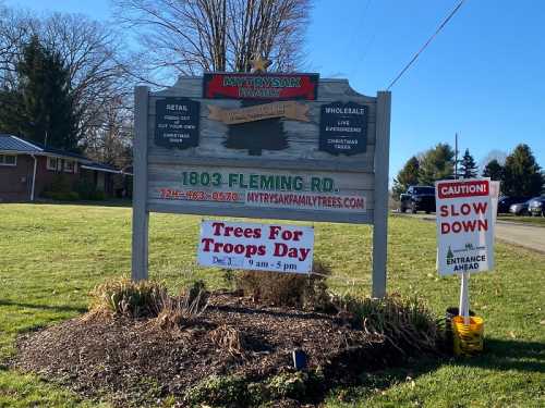 Sign for Mytrysak Family Trees, featuring retail and wholesale options, with a "Trees For Troops Day" event announcement.