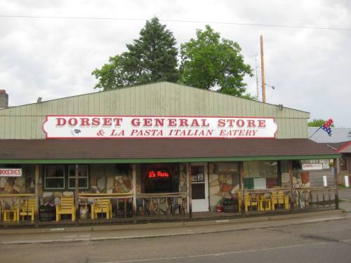 Exterior of Dorset General Store & La Pasta Italian Eatery, featuring a green facade and outdoor seating.