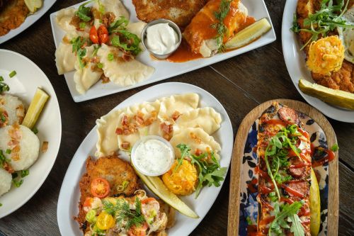 A variety of delicious dishes including pierogi, chicken, and a colorful salad, garnished with herbs and sauces.