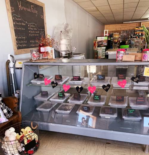 A display case with various desserts, labeled with colorful signs, in a cozy shop setting.