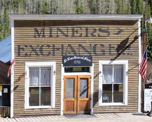 Historic wooden building with "Miners Exchange" sign, featuring large windows and a welcoming entrance.