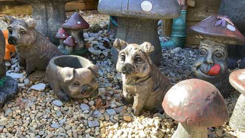 A collection of decorative pig figurines and mushroom sculptures in a garden setting.