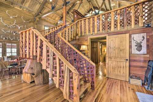 A rustic wooden interior featuring a staircase, wooden walls, and decorative antlers on the ceiling.