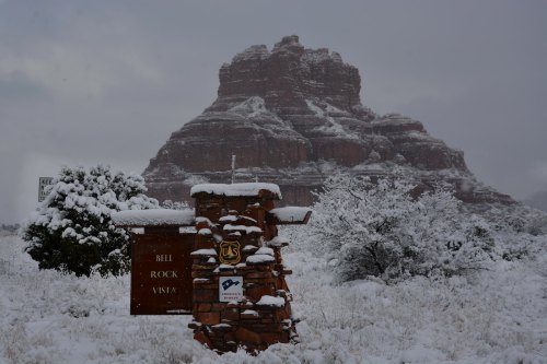 Snow-covered landscape featuring a sign for Bell Rock Vista with a rocky formation in the background.
