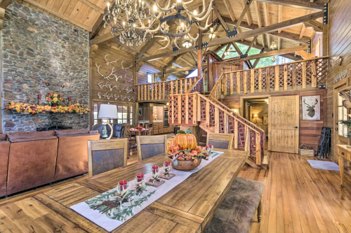Cozy rustic dining area with a wooden table, chandelier, and staircase in a warm, inviting cabin setting.