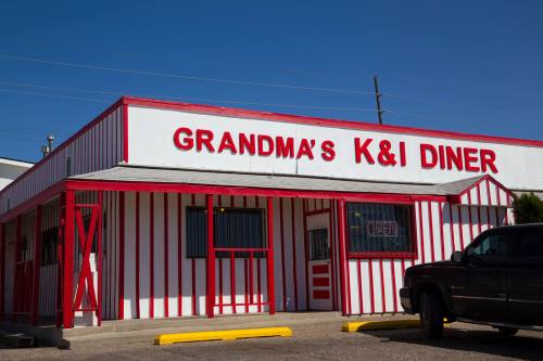 Exterior of Grandma's K&I Diner, featuring red and white striped walls and a bright blue sky.