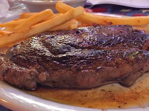 A juicy steak on a plate, accompanied by golden French fries.