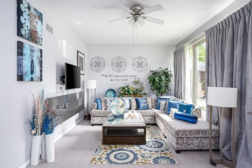 Bright living room with a patterned sofa, decorative pillows, a coffee table, and large windows letting in natural light.