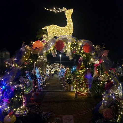 A festive pathway adorned with colorful lights and decorations, featuring a glowing reindeer at the center.