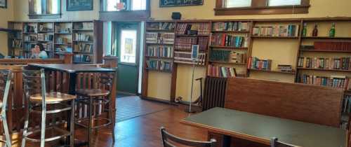 Cozy café interior with bookshelves, tables, and a person sitting at a table near the entrance.