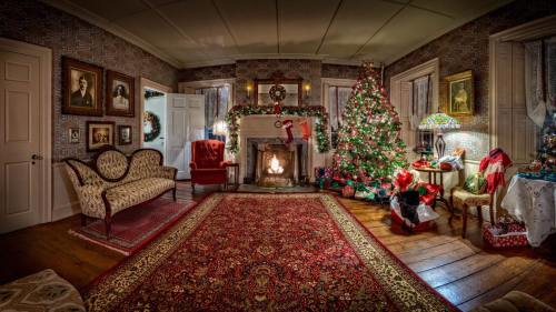 Cozy holiday living room with a decorated Christmas tree, fireplace, and festive decor, featuring a warm, inviting atmosphere.