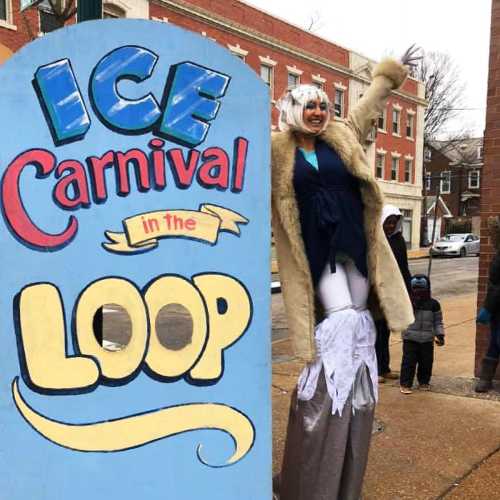 A person in a costume poses next to a colorful sign that reads "Ice Carnival in the Loop."