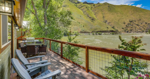 A scenic deck overlooking a river, surrounded by lush green hills and trees under a blue sky.