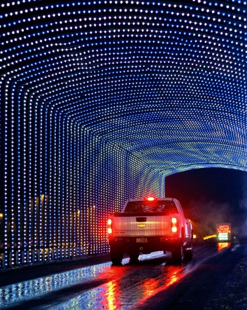 A truck drives through a colorful tunnel of lights, creating a festive and vibrant atmosphere.