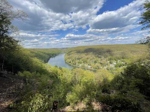 A scenic view of a river winding through lush green hills under a partly cloudy sky.