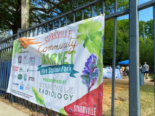 Banner for Starkville Community Market at Fire Station Park, featuring sponsors and colorful illustrations of produce.