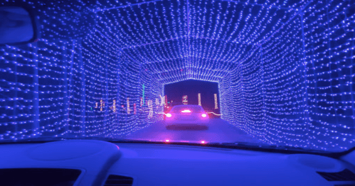 A car drives through a tunnel illuminated with vibrant blue lights.