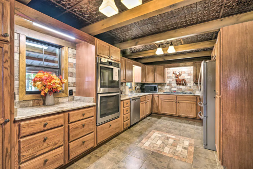 A spacious kitchen with wooden cabinets, granite countertops, and modern appliances, featuring a decorative floral arrangement.