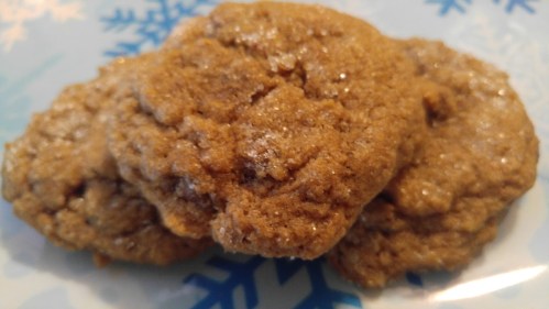 Three freshly baked cookies on a blue plate with snowflake patterns.